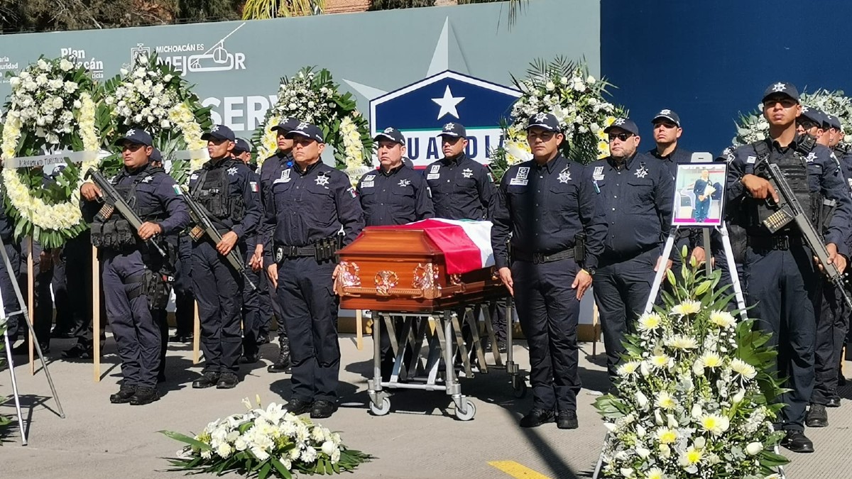 Oficiales de la SSE de Michoacán haciendo guardia al lado del féretro de Karla Lorena Patiño Gutiérrez con coronas fúnebres alrededor