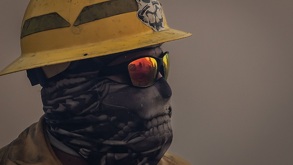 Persona con casco, gafas y cubrebocas mientras combate un incendio forestal.