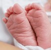 Se observan los pies de un recién nacido, tapado con una cobija.