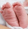 Se observan los pies de un recién nacido, tapado con una cobija.