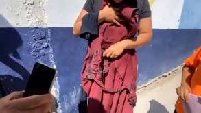 Mujer sostiene ropa quemada de una niña en una primaria de Tehuacán, Puebla.