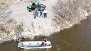 Se observan varios hombres y una lancha dentro de un cuerpo de agua.