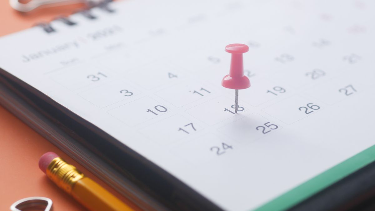 Un calendario sobre una mesa, marcado en la casilla de una fecha con un tachuela de color rosa
