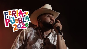 Hombre con sombrero y barba sosteniendo un micrófono mientras canta.