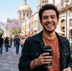 Joven con café en la mano en una calle de Jalisco durante el día | Generado con IA