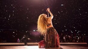 Shakira cantando sobre el escenario y al fondo miles de personas presenciando el momento.