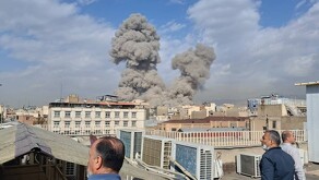 Varias personas observan mientras una columna de humo señala el lugar donde se produjo una explosión en Teherán hoy 28 de febrero.