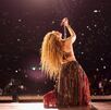 Shakira cantando sobre el escenario y al fondo miles de personas presenciando el momento.