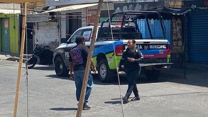 Mujer policía hablando con un civil junto a una patrulla oficial.