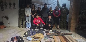 Cuatro hombres y cuatro mujeres con la cara blureada con dos oficiales de la Marina a los lados, además de armas y equipo táctico delante