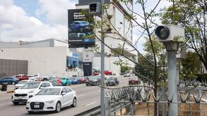 Automóviles circulando por la ciudad de Puebla y una cámara de fotomultas registrando las infracciones