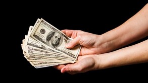 Mano agarrando dólares estadounidenses.