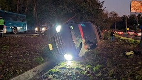 Camioneta de pasajeros volcada sobre una canaleta en el camellón de Carretera a Nogales con el cristal delantero estrellado y la luz de los faros encendidos