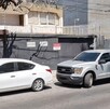 Camioneta gris y autos blancos estacionados al exterior de una vivienda con portón negro y sellos de clausura puestos
