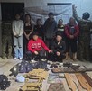 Cuatro hombres y cuatro mujeres con la cara blureada con dos oficiales de la Marina a los lados, además de armas y equipo táctico delante