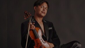 Joven sosteniendo un violín vestido con un saco negro