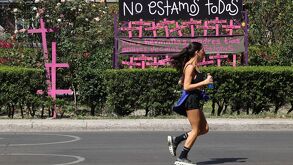 Mujer camina cerca de un mural de protesta por los casos de feminicidio