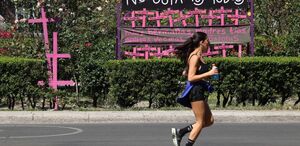 Mujer camina cerca de un mural de protesta por los casos de feminicidio