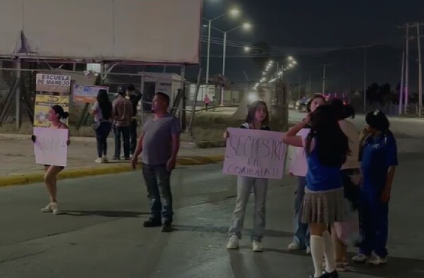 Se observa a un hombre y varias mujeres con cartelones en la mano en medio de la calle.