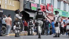 Policías armados resguardan un bar tras una riña registrada en el lugar.