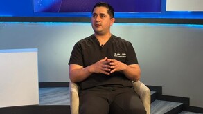 Se observa un hombre sentado, viste uniforme color azul marino y está de perfil.