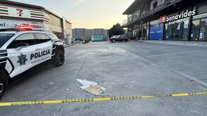 Se observan varios negocios, en la parte superior se ven destrozos y hay una cinta amarilla de precaución.