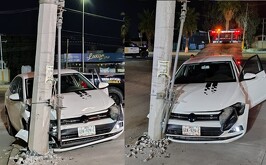 Automóvil blanco chocado contra un poste.