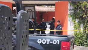 Oficiales de la Policía Municipal de Zapopan al interior de una casa naranja con portón negro y una patrulla estacionada afuera