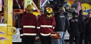 Personal de Protección Civil mira hacia arriba junto a un juego mecánico.