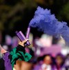 Brazo de una mujer durante una marcha del 8M con una bengala de humo morado en la mano.