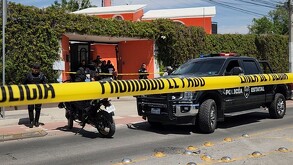 Oficiales y patrulla de la Fiscalía del Estado de Jalisco al exterior de una casa color naranja acordonada por cintas policiacas