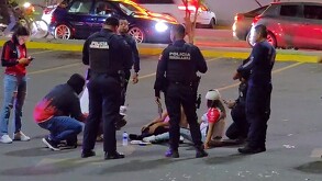 Oficiales de la Policía de Guadalajara atendiendo a personas que están sentadas en el suelo con autos pasando detrás