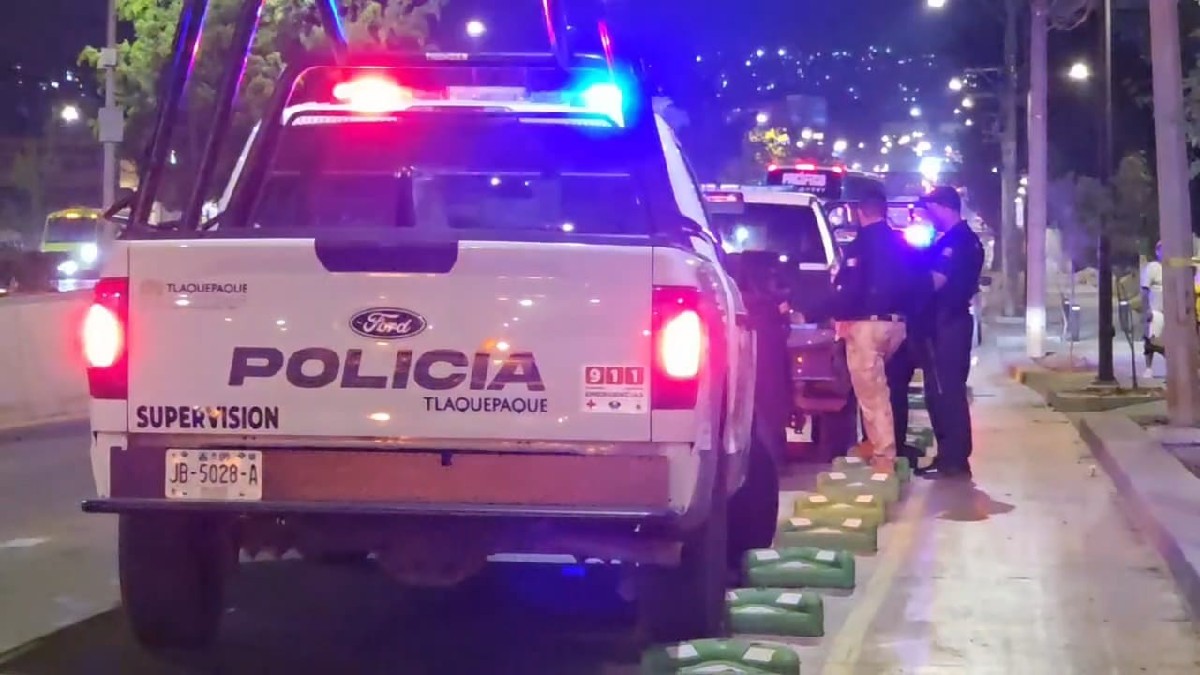 Patrulla de la Policía Municipal de Tlaquepaque con las sirenas encendidas y oficiales parados a un lado