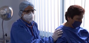 Se observa a un doctor con uniforme y una mujer paciente con cubrebocas.