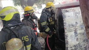 Tres elementos de Protección Civil y Bomberos de Guadalajara observando el interior de una combi luego de haber apagado el incendio del vehículo