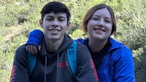 Se observa a un joven y una muchacha que están sonriendo y la chica abraza al hombre.