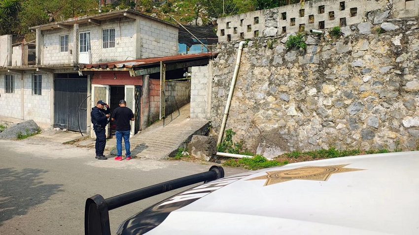 Policía y un hombre parados en una acera afuera de una vivienda, en Veracruz.