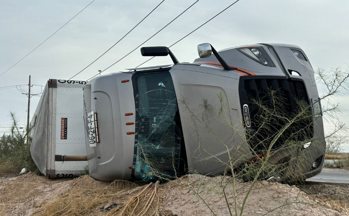 Tráiler gris que transportaba cobre volcado sobre la carretera.