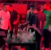 Hombres dentro de una discoteca de Perú con luz tenue roja parados alrededor de mesas con botellas de cristal vacías