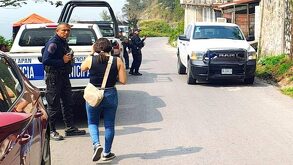 Mujer camina junto a una patrulla de policía de Veracruz estacionada, afuera de una vivienda.