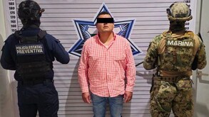 Hombre de camisa naranja junto a elementos de la policía estatal de Puebla y un marino.