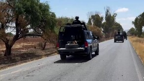 Patrullas con oficiales de la Policía del Estado de Zacatecas transitando sobre una carretera con árboles y maleza a los costados