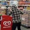 Mujer vista de espaldas con un abrigo a cuadros y las manos levantadas adentro de un Bodega Aurrera con empleados frente a ella