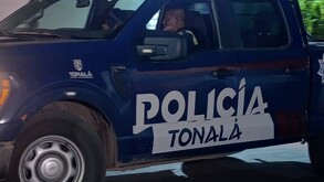 Vista lateral de una patrulla de la Policía Municipal de Tonalá con dos oficiales dentro de la unidad viendo hacia un costado