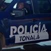 Vista lateral de una patrulla de la Policía Municipal de Tonalá con dos oficiales dentro de la unidad viendo hacia un costado