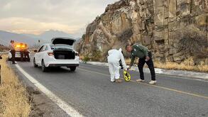 Se observa a una persona con uniforme de perito color blanco, varios autos sobre la carretera.