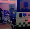 Paramédicos de la Cruz Verde ingresando a un hospital a un joven acostado en una camilla y cubriéndose con un abrigo azul tras salir de una ambulancia