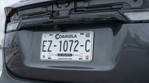 Se observa un carro color gris oscuro con una placa visible.
