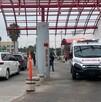 Se observa una ambulancia estacionada afuera de un edificio y un vehículo enfrente.