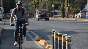 Persona con casco anda en bicicleta por una ciclovía de Puebla.